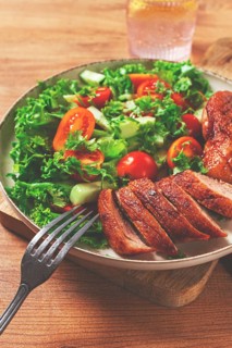 Delicious grilled duck breast served with fresh garden salad and cherry tomatoes at a rustic dining