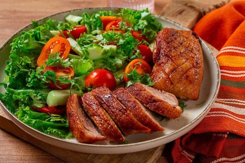 Delicious grilled duck breast served with fresh garden salad and cherry tomatoes at a rustic dining