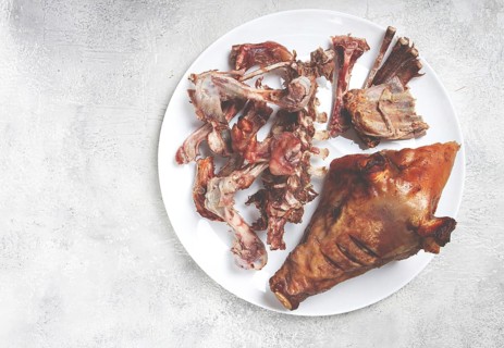 Roast pork head, with remnants of bones and meat, on a white platter, no people, close-up