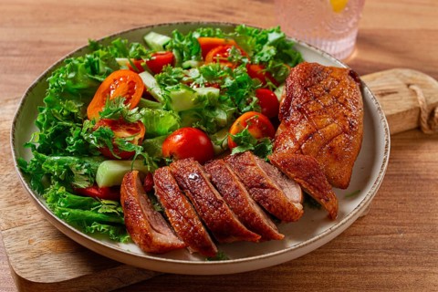 Delicious grilled duck breast served with fresh garden salad and cherry tomatoes at a rustic dining