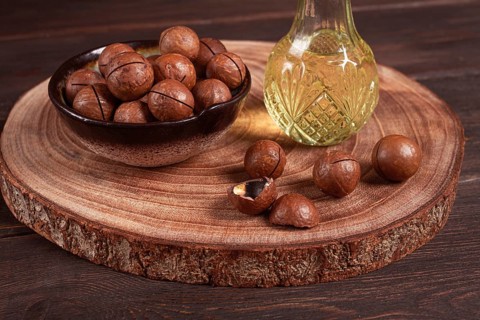 Bottle of macadamia oil, on a wooden board, with macadamia nuts, wooden background, selective