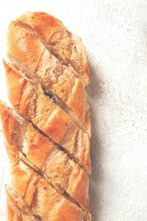 Garlic bread, baguette with garlic butter and herbs, on a light table, top view
