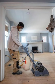 Detroit, Michigan - Workers sand a floor as they remodel a house in the Morningside neighborhood.