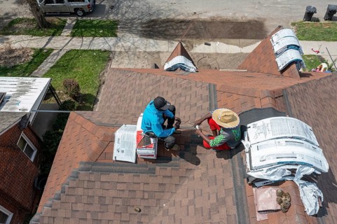 Detroit, Michigan - Workers take a break while re-roofing a house they are remodeling in the