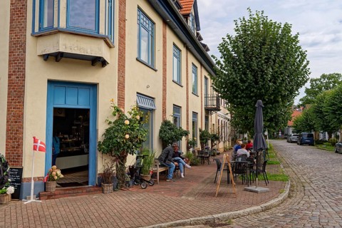 Cafe in the town centre, on the corner of Neuer Damm and Lange Straße, both with cobblestones.