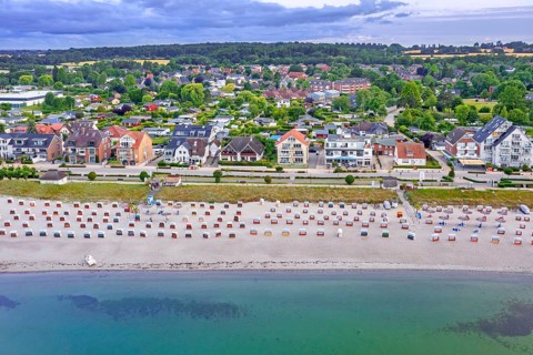 Aerial view over sandy beach with roofed wicker beach chairs and seaside resort Haffkrug along the