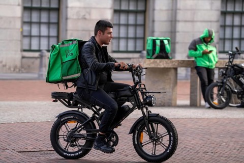 Bicycle traffic in Groningen, Uber Eats, courier driver with e-bike in moped style, fatbike,