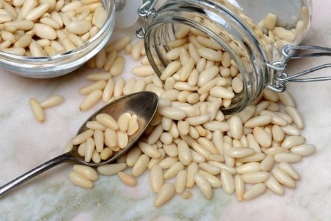 Pine nuts in glass container and spoon, Pinus pinea