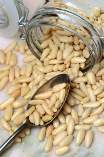 Pine nuts in glass container and spoon, Pinus pinea