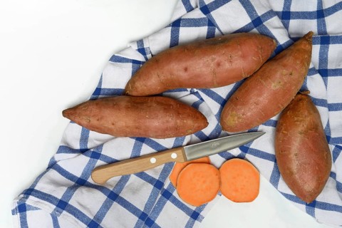 Sweet potatoes with kitchen knife on kitchen towel, Ipomoea batatas