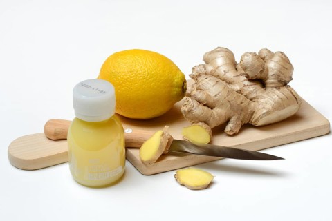 Ginger root and lemon on cutting board and ginger shot