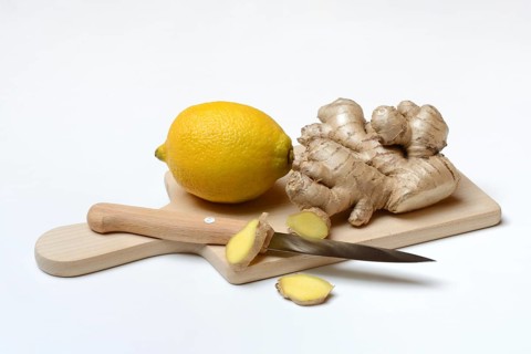 Ginger root and lemon on cutting board with knife, ginger slices, Zingiber officinale