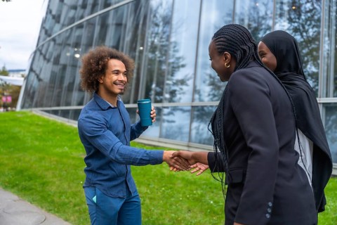 Diverse business professionals meeting and exchanging a friendly handshake outdoors in a modern
