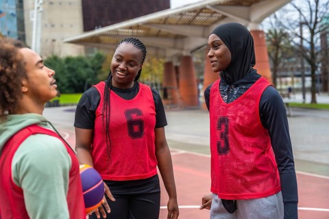 Group of diverse young athletes, including men and women, wearing red training bibs and a hijab,