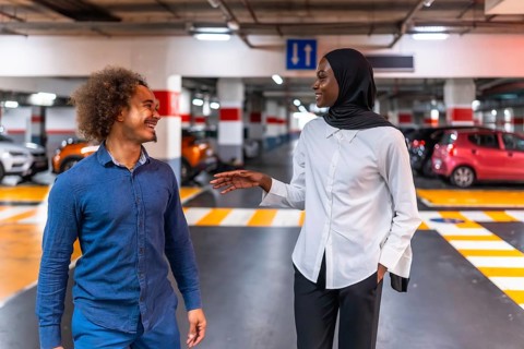 Diverse young couple smiling and talking, sharing a happy moment with engaging conversation in a