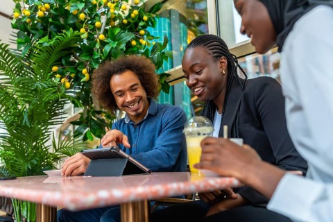 Diverse group of young adult friends enjoying a social gathering in a modern cafe, laughing and