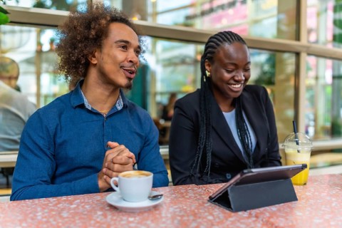 Two diverse business professionals are meeting in a relaxed cafe environment, discussing ideas and