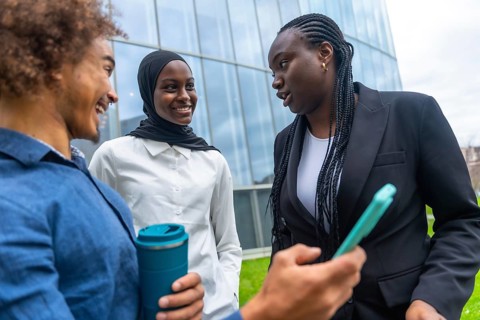 Group of multi ethnic colleagues engaging in a friendly conversation outside a modern office