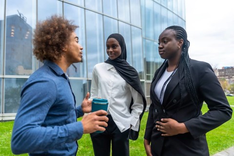 Diverse business professionals standing outdoors, engaging in an informal discussion during a