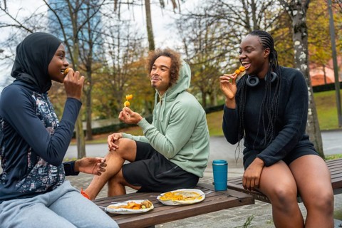 Group of diverse urban friends enjoying a casual snack from a street vendor while sitting outdoors