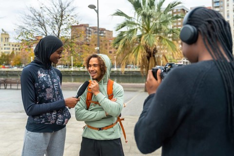Content creators filming an outdoor interview with a smiling man, capturing diverse perspectives