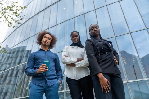 Diverse business team of young professionals standing together with confident expressions against a
