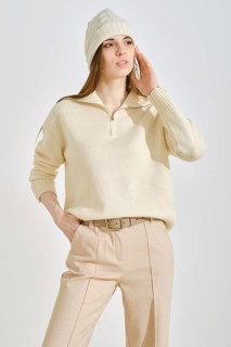 A woman wearing a light cream sweater and beige trousers, perfect for a casual outing. She