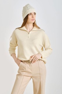 A woman poses confidently in a cozy cream sweater and stylish beige pants, perfect for a casual