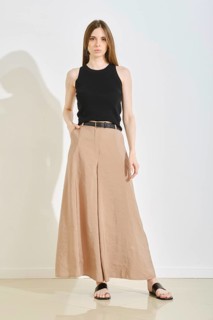 A young woman showcases a stylish outfit with a fitted black tank top and elegant beige wide-leg