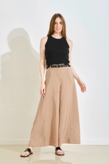 A young woman stands confidently in a trendy outfit, showcasing wide-legged beige pants and a black