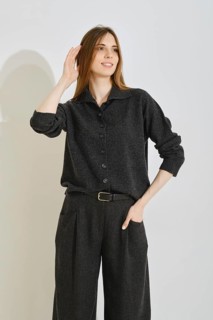 A young woman playfully touch her smooth long hair wearing trendy outfit featuring a dark button-up