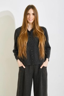 Smiling woman poses in a comfortable black outfit featuring a soft button-up top and loose pants on