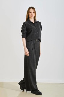A woman showcases a stylish black ensemble featuring a button-up top and wide-legged pants.