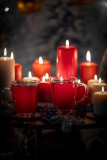 Close-up of red and white candles with tea in cups, Christmas background