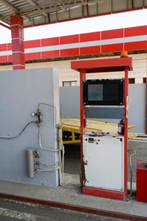 Red gas pump with screen and cables in front of a grey wall, gas filling station, Sewan,