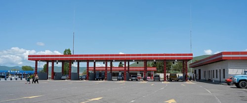 Large red gas station with several cars, pillars and adjacent building, gas filling station, Sewan,