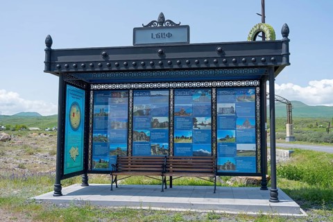 Bus stop with information posters surrounded by rural landscape under blue sky, bus stop at Lake