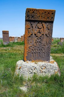Standing tombstone with complex patterns and orange patina in a green landscape, crossstones,
