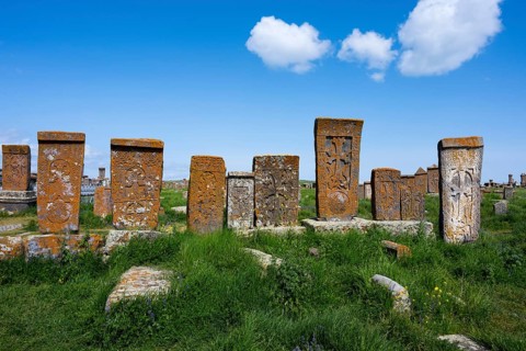 Old crossstones on a green field under a blue sky with clouds, crossstones, khachkars, world's