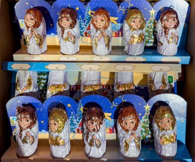 Chocolate Christmas angel in musical instruments printed on colorful staniol paper on a retail