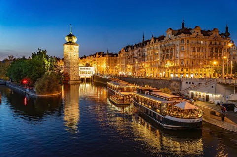 Hotel boats on the banks of the Vltava river and Sitkov water tower at dusk, Prague, Czech Republic