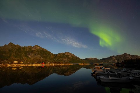 Northern lights are reflected in the fjord in Norway. Aurora Borealis over Festvåg near Bodø,