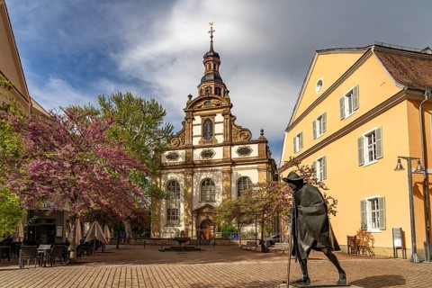 Sculpture of a Saint James Pilgrim on Maximilianstraße and the Trinity Church in Speyer,