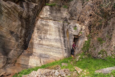 Tourist in the quarry near the prehistoric Palli-Lakka dragon houses Drakospita near Styra, island