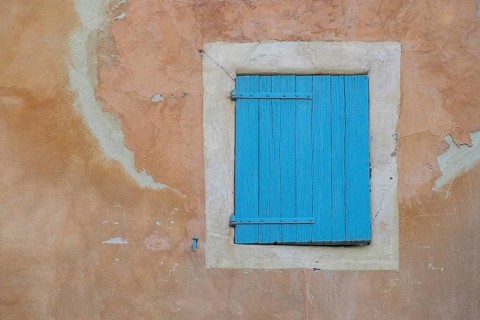 A dilapidated, blue-painted shutter on a faded wall, village of Menerbes, Luberon, Vaucluse,