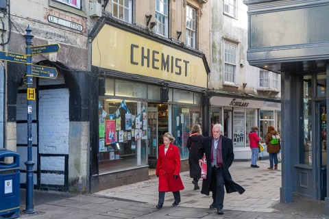 Shops and shoppers in Little Brittox street, Devizes, Wiltshire, England, UK traditional Chemist