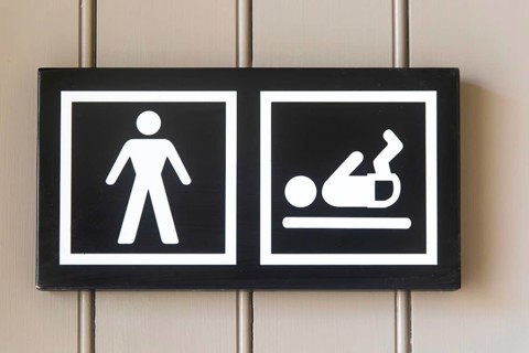 Pictogram sign for nappy changing facility in male bathroom toilets, UK