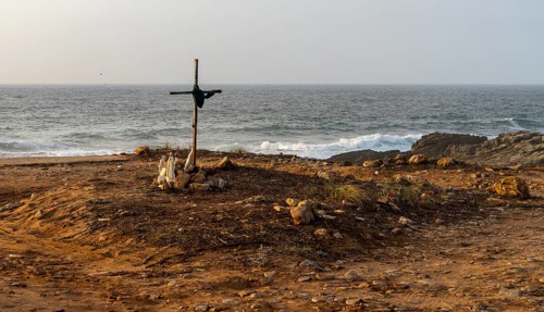 Religious scene, temporary Christian cross on the coast Farol de Cabo Raso lighthouse, São Bras de