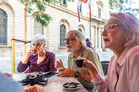 Group of diverse senior friends smiling and interacting socially while drinking coffee at an