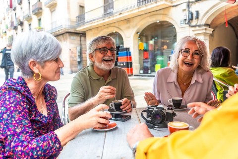 Happy senior friends gathering at an outdoor cafe, drinking coffee, and having a lively